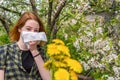 Season allergy to flowering plants pollen. Young woman with dandelion bouquet and paper handkerchief covering her nose in garden. Royalty Free Stock Photo