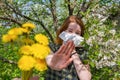 Season allergy to flowering plants pollen. Young woman with paper handkerchief covering her nose in garden and doing stop sign to Royalty Free Stock Photo