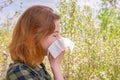 Season allergy to flowering plants pollen. Young woman with paper handkerchief in hand covering her nose in garden. Teen girl Royalty Free Stock Photo