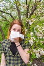 Season allergy to flowering plants pollen. Young woman with paper handkerchief in hand covering her nose in garden. Teen Royalty Free Stock Photo