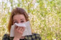 Season allergy to flowering plants pollen. Young woman with paper handkerchief in hand covering her nose in garden. Teen girl Royalty Free Stock Photo