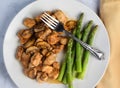 season chicken bites top with mushrooms with asparagu