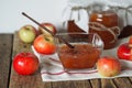 Season for making jam for future use. Apple jam in a salad bowl on a napkin on a wooden table with jars of jam in the background Royalty Free Stock Photo