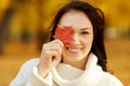 Happy young woman with maple leaf in autumn park