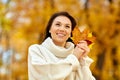 Happy young woman with maple leaves in autumn park