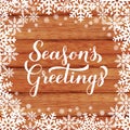 SeasonÃ¢â¬â¢s Greetings calligraphy hand lettering on wood background with snowflakes. Merry Christmas and Happy New Year typography Royalty Free Stock Photo