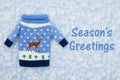 Season`s Greetings message on with Christmas sweater with a reindeer and snowflakes