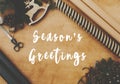 Season`s greetings text sign on christmas rustic flat lay, stylish wrapping paper, wooden reindeer, pine branches and cones,