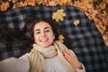 Season, technology and people concept - beautiful young woman lying on ground and autumn leaves and taking selfie with Royalty Free Stock Photo