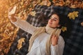 Season, technology and people concept - beautiful young woman lying on ground and autumn leaves and taking selfie with Royalty Free Stock Photo