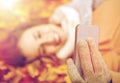 Woman on autumn leaves taking selfie by smartphone Royalty Free Stock Photo