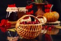 Season of vitamin berries: ripe cranberries in a wicker basket against the background of jars of pumpkin jam, fruits, dark Royalty Free Stock Photo