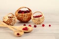 Season of vitamin berries: ripe cranberries in wicker baskets, on wooden spoons on a light background, space for text Royalty Free Stock Photo