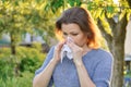 Seasonal allergies, woman with nasal wipe, sneezing, wiping nose outdoor