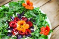 Seasonal arugula salad with goat cheese, roasted red peppers and edible nasturtium flowers