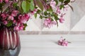 Seasonal bouquet of pink blossom apple branches in a ceramic vase on a wooden table. Shallow depth of field