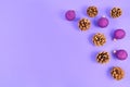 Seasonal Christmas flat lay with fir cones and purple gittering tree baubles on right side and empty purple copy space Royalty Free Stock Photo