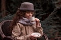 Autumn child girl drinking hot beverage in the garden cafe