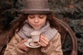 Autumn child girl drinking hot beverage in the garden cafe