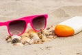 Seasonal concept, heap of shells, sunglasses and sun lotion on sand at beach Royalty Free Stock Photo