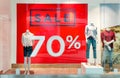 Seasonal discounts in the store. Big red banner with text SALE 70 percent on a shop windows and mannequins dressed in