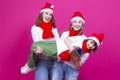 Seasonal Holidays. Three Positive Caucasian Girls With Santa Hats Having Fun While Lifting Teenage Girl Holding Wrapped Golden Royalty Free Stock Photo