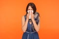 Seasonal influenza. Portrait of flu-sick brunette woman wrapped in scarf, blowing her nose and sneezing in napkin Royalty Free Stock Photo