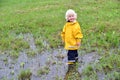 Seasonal outdoor portrait of a cute little blond boy standing in the puddle Royalty Free Stock Photo