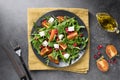 Seasonal salad with persimmon, arugula on dark table