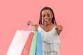 Seasonal sale or promo. Excited young black woman with colorful shopping bags pointing at camera over pink background Royalty Free Stock Photo