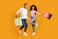 Seasonal Sales Concept. Joyful Young Arab Couple Jumping With Colorful Shopping Bags