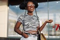 Happy black young woman walking in the mall after shopping for clothes, looking out the store window Royalty Free Stock Photo