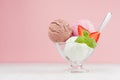 Seasonal sweet dairy dessert - ice cream scoops different flavor with spoon, strawberry slices, mint in elegant bowl in modern.