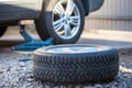 Seasonal winter tyre change. Snow tire lying on ground, is ready to install, spring Royalty Free Stock Photo