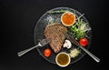 Seasoned grilled steak with utensils and sauce