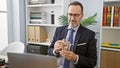 Seasoned manager in grey hair and glasses, a middle age man, diving into serious money business, counting dollars at his office Royalty Free Stock Photo