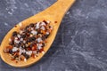 Seasoning red and black on a wooden spoon on a dark gray background. Black pepper  chili pepper  sea salt. Royalty Free Stock Photo