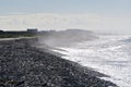 Seaspray fogs stony beach as friends look out to sea Royalty Free Stock Photo