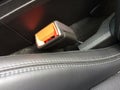 Seat belt lock in car made of black orange plastic near leather stitched seat