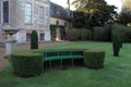 Seat built into hedge work and vintage urn on a pedestal in a garden