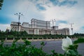 Seat of Romanian parliament, huge building in the centre of Bucharest, Romania on a cloudy summer day. View through the bushes. Royalty Free Stock Photo