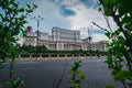 Seat of Romanian parliament, huge building in the centre of Bucharest, Romania on a cloudy summer day. View through the bushes. Royalty Free Stock Photo