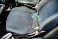 The seat of a vandalized car with broken smashed glass covering the seat