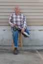 Seated amputee man with prosthetic leg crossed, holding with both hands