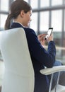 Seated business woman with phone in blurry office Royalty Free Stock Photo