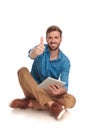 Seated casual man working on tablet makes the ok sign