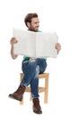 Seated cool guy looking away with newspaper in hands