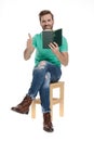 Seated cool man showing ok gesture with book in hand