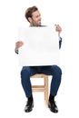 Seated fashion guy holds blank carton board while looking away