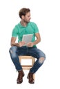 Seated fashion guy looking away with pad in hands
